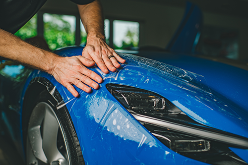 Montering av Paint Protection Film (PPF) på blå bil for å beskytte lakken mot steinsprut, riper og slitasje.