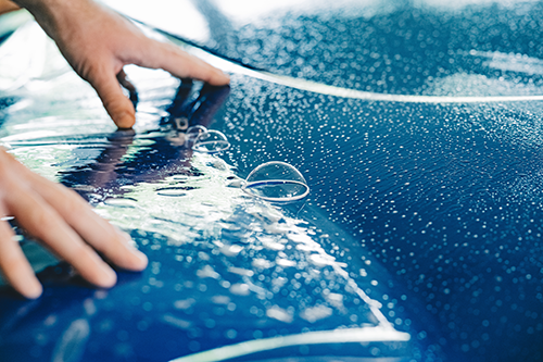 Påføring av Paint Protection Film (PPF) på bil med våtmontering for beskyttelse mot steinsprut, riper og slitasje.